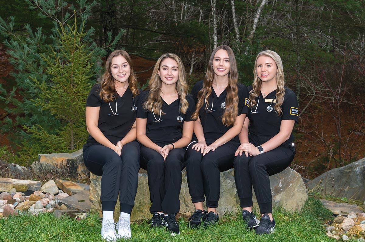 Photo of 4 Dal Bachelor of Science in Nursing students wearing their Dal nursing uniforms. Photo taken at Moments in Time Photography Studio in Halifax