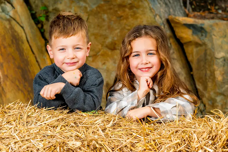 Photo of a little boy and girl next to a bale of hay. Photo taken at Halifax photography studio