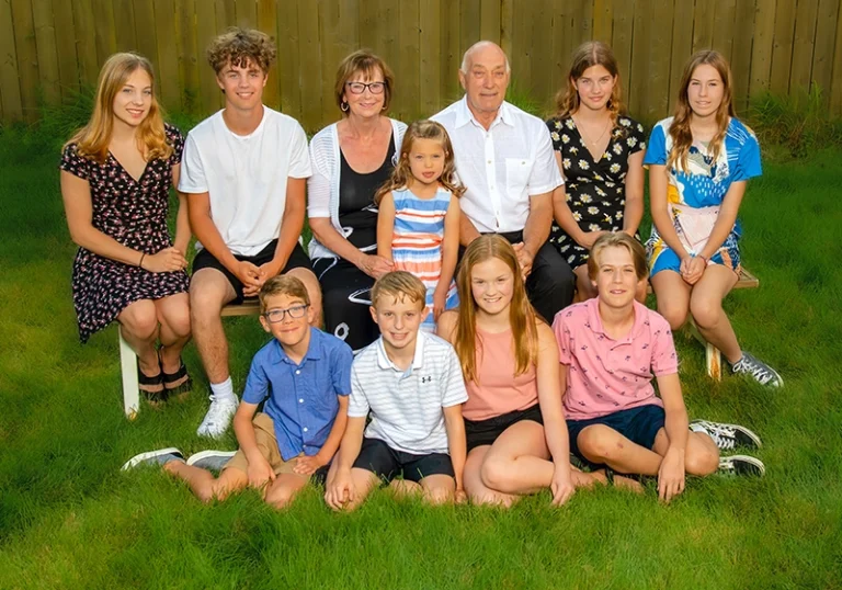 Grandparents surrounded by all of their grandchildren in a beautiful outdoor setting, captured together in a joyful family portrait at a Family Portrait Studio.