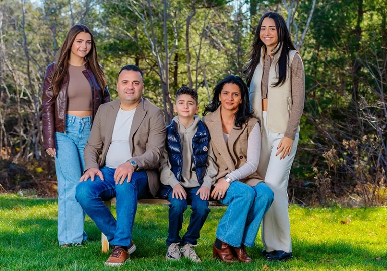 Mom and dad with their three children, posing together in a beautiful garden, captured in a joyful family portrait outdoors surrounded by lush greenery and colorful blooms.