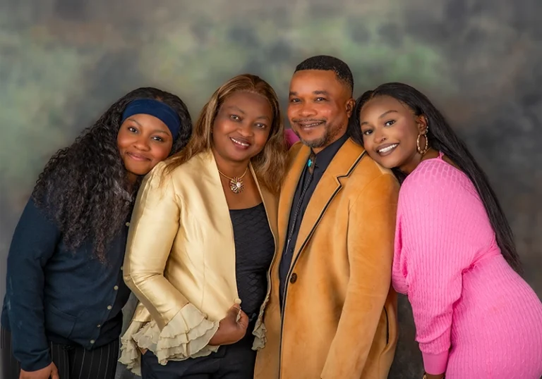 Dad with his wife and their two adult daughters, posing together in a Family Portrait Studio, captured in a warm and joyful family moment.