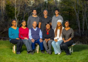 Mother and father sitting on a bench with their children and their respective husbands and wives, captured together in a joyful family portrait in an outdoor setting at a Family Portrait Studio.