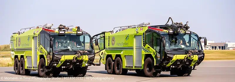 Two bright yellow Halifax Stanfield airport fire trucks parked on the runway, showcasing essential emergency vehicles specialized for airport firefighting services, captured by Moments in Time Photography Studio